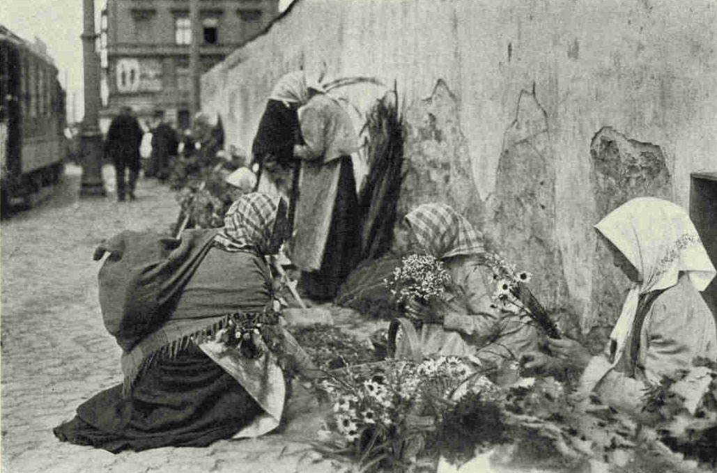 A Corner of The Riga Flower MarketThe flower girls of Latvia are more often than not wrinkled with age and bent by toil. But Latvia owes a heavy debt to its women, who drive the wagons, harvest the flax, pile up the grain, tend the cattle, sweep the streets, pull the carts, run the hotels, tend the street markets, keep the stores, shovel the sawdust, and juggle the lumber.Photograph by J. Reeksta