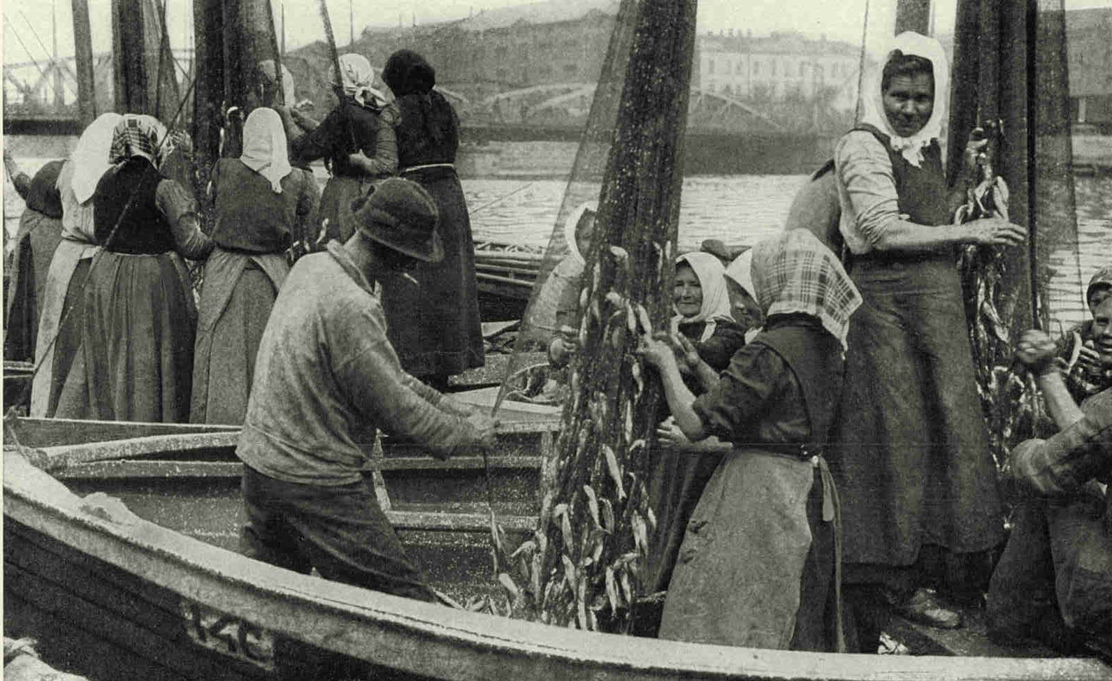 Fishing Smacks in The Harbor of LiepajaThe Latvian is frugral and every fish is salvaged if possible. The women are here shown picking some of the catch out of the meshes of the nets. Tne years ago 10,000 Lettish fishermen earned their living from the Baltic, but during the World War they were forbidden to continue this pursuit. The survivors are now building up the industry again.Photograph by Ernest Peterfly